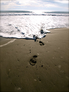 photography of footprint in the sand washed away by sea waves thumbnail