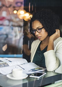 woman sitting in front of table while reading newspaper thumbnail