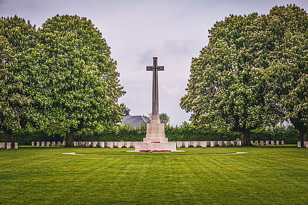 gray concrete cross statue between trees at daytime thumbnail