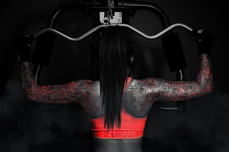 woman wearing orange sports bra using gray lat-pull down machine thumbnail