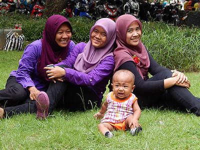 three woman and baby sitting at the grass while taking them a group picture thumbnail