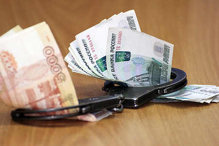 banknotes on black hand cuffs placed on brown wooden board thumbnail
