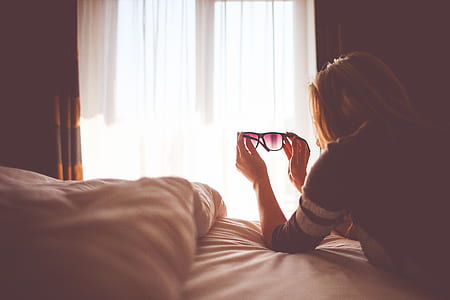 woman holding black sunglasses inside bedroom thumbnail