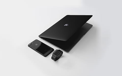 MacBook black beside iPhone and Apple Watch on white surface thumbnail