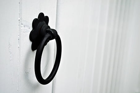 black steel ring door knocker on white wooden wall thumbnail