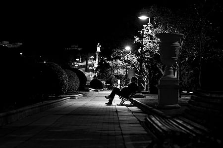 grayscale photo of person sitting on bench near street light thumbnail