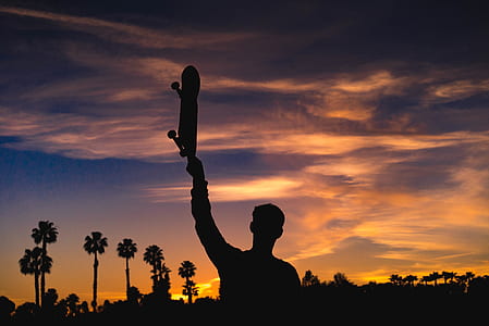 silhouette of person holding up skateboard thumbnail