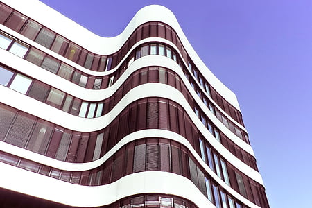 low angle view of white and brown glass building with purple sky thumbnail