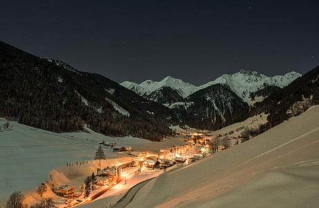 snow covered village overlooking mountains during nighttime thumbnail