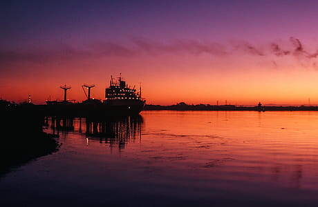 Cranes and transport ship docked at harbor during sunset thumbnail