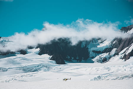 white, black, and yellow helicopter on mountain under blue sky thumbnail