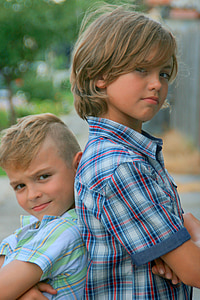 two boy's standing back to back of each other thumbnail