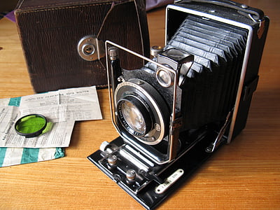 black land camera with green lens cover on brown wooden board thumbnail