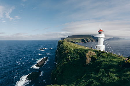 white lighthouse over green mountain thumbnail