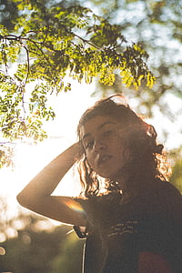 woman standing while touching her hair under green tree thumbnail