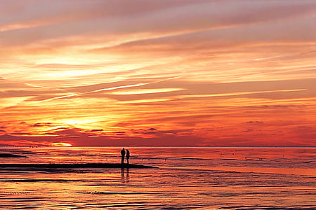 silhouette of two persons beside sea during sunset thumbnail