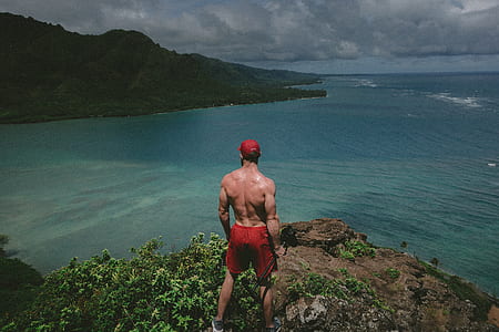 man standing on edge of cliff at sea thumbnail