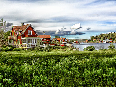 photo of a brown house near body of water and grass land thumbnail