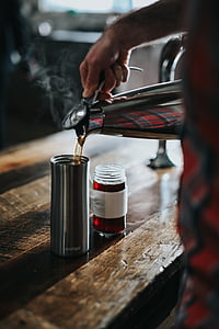 person pouring coffee on tumbler near table during daytime thumbnail