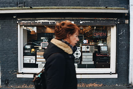 woman in black fur jacket standing in front of radio storefront thumbnail