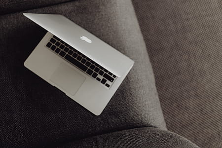 Close up view of closed laptop lying on grey armchair thumbnail