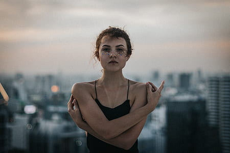 woman holding her shoulders on top of building thumbnail