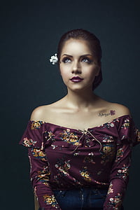 woman with burgundy off-shoulder floral blouse looks up thumbnail