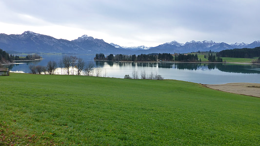 green grass field near body of water under blue sky at daytime thumbnail