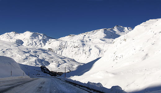 snow covered concrete road between snow covered mountains at daytime thumbnail