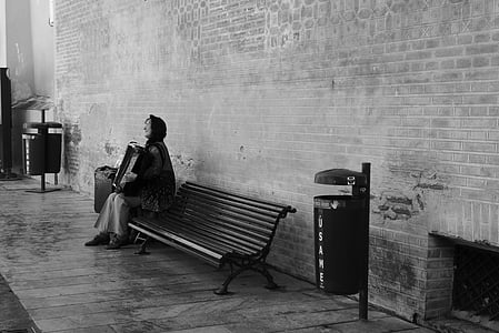 grayscale photo of woman sitting on bench thumbnail