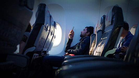 man wearing black dress shirt holding phone in the airplane seat thumbnail