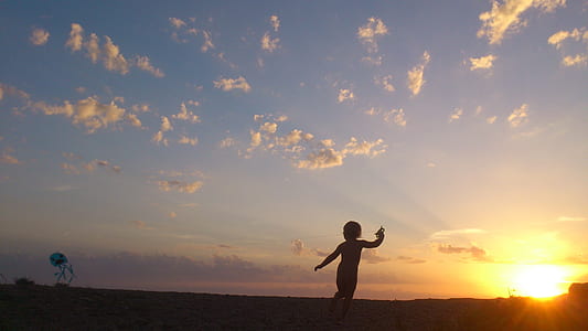 silhouette photography of kid running during golden hour thumbnail