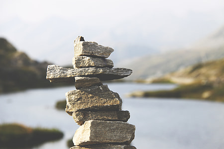 shallow photography of cairn with background of mountain and large body of water during daytime thumbnail