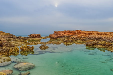 photo of body of water surrounded by rocks thumbnail