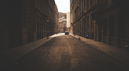 asphalt road between brown buildings during daytime thumbnail