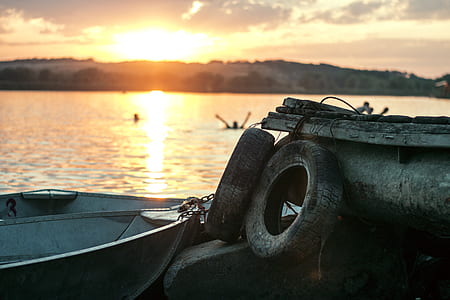 White Boat on Dock Near Two Auto Tires during Sunset thumbnail