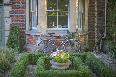 Grey Mountain Bike Leaning on Brown Wall Brick in Garden thumbnail