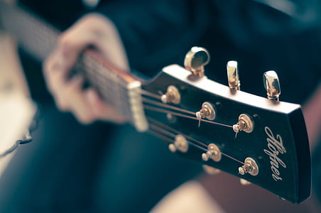 selective focus photography of person playing guitar thumbnail