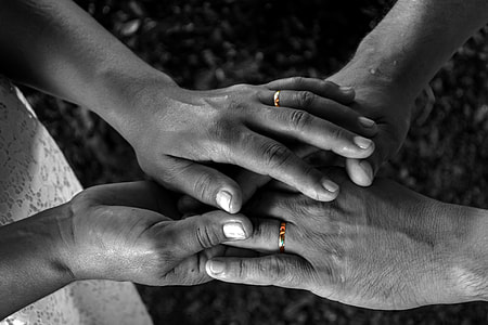 selective color photography of hands with gold-colored band rings thumbnail
