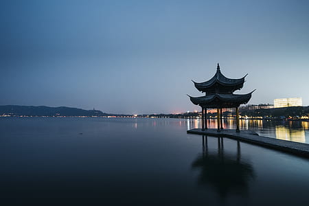 photo of brown wooden dock with shed near calm body of water during nighttime thumbnail