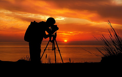 silhouette of man taking photo of sunset thumbnail
