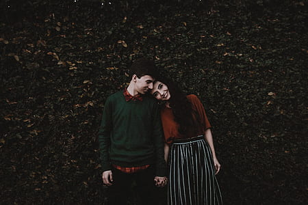 man in green sweater beside woman in brown dress and black skirt thumbnail