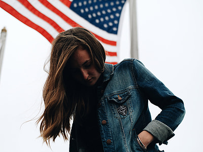 Girl standing under American Flag thumbnail