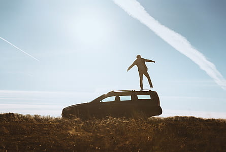 silhouette of person standing on station wagon during daytime thumbnail