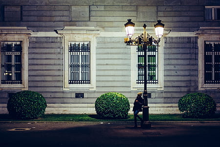 woman leaning on black steel post lamp near house thumbnail