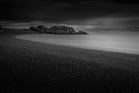 grayscale photo of body of water near mountain range thumbnail