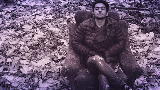 Man in Black Puffer Jacket and Distress Jeans Sitting in Couch thumbnail