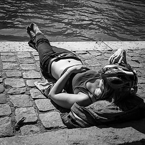 grayscale photo of a woman lying near a body of water thumbnail