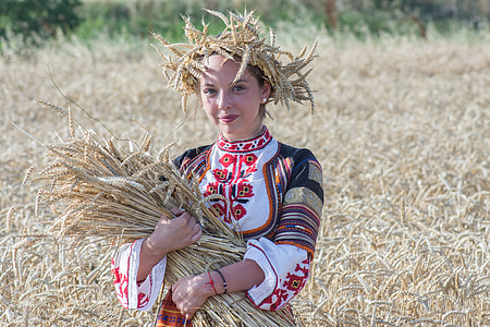 woman wearing white and red long-sleeved dress holding bunch of wheat barley thumbnail