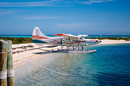 white, red, and blue plane on body of water thumbnail